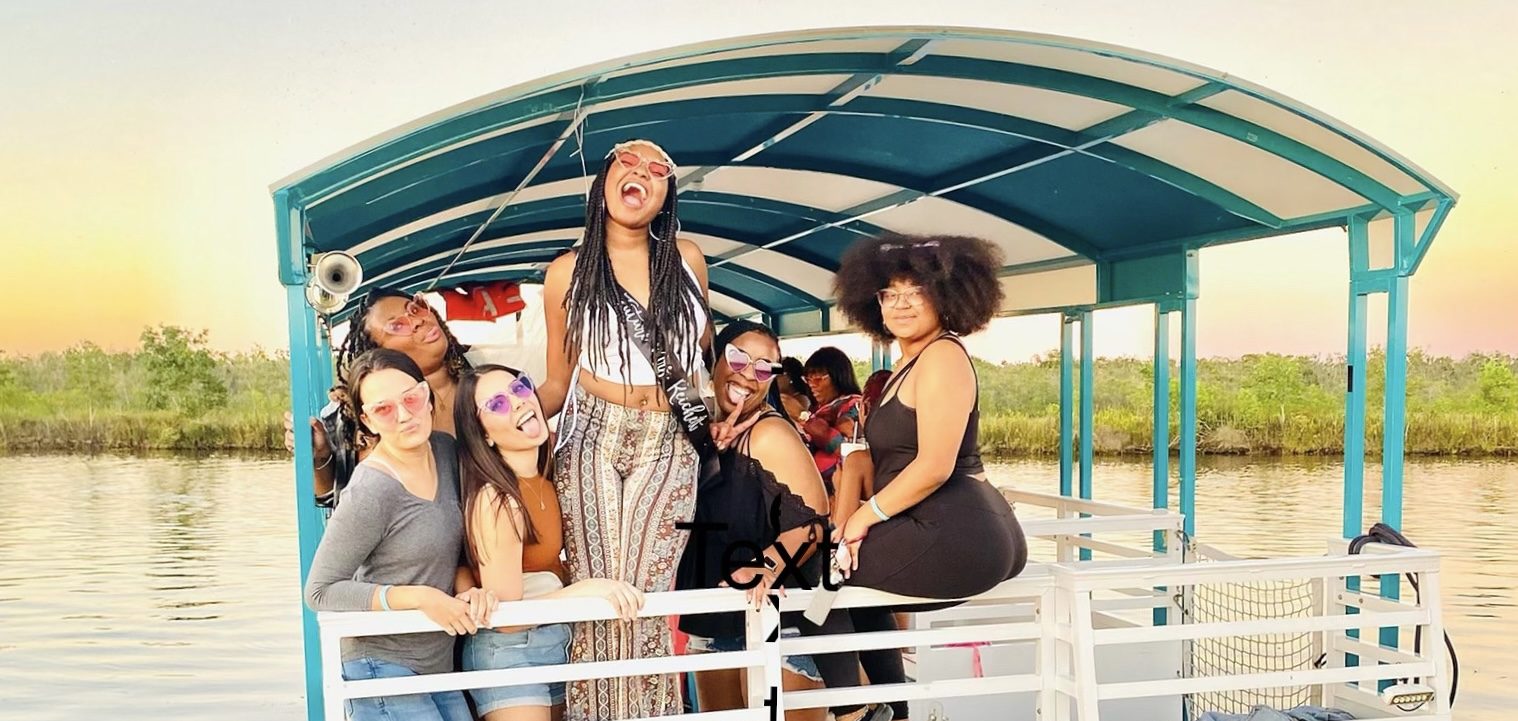 a woman standing in front of a New Orelans party boat in a swamp